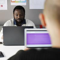 Two men sitting opposite each other, working on their laptops