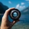 Hand holding a camera lens focusing on faraway mountains