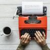 A person with writer's block struggling to write on a red typewriter