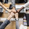 Five coworkers fist-bumping in a culture of continuous improvement