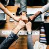 View from above of five coworkers fist-bumping over their computers