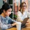 A mentor and mentee talking and looking at a laptop