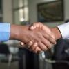 Two people shaking hands after earning a promotion