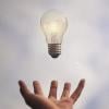 Light bulb hovering over a person's hand