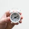 Hand holding miniature white alarm clock