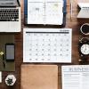 Computer, calendar, projections, and business paper all laid out on a table